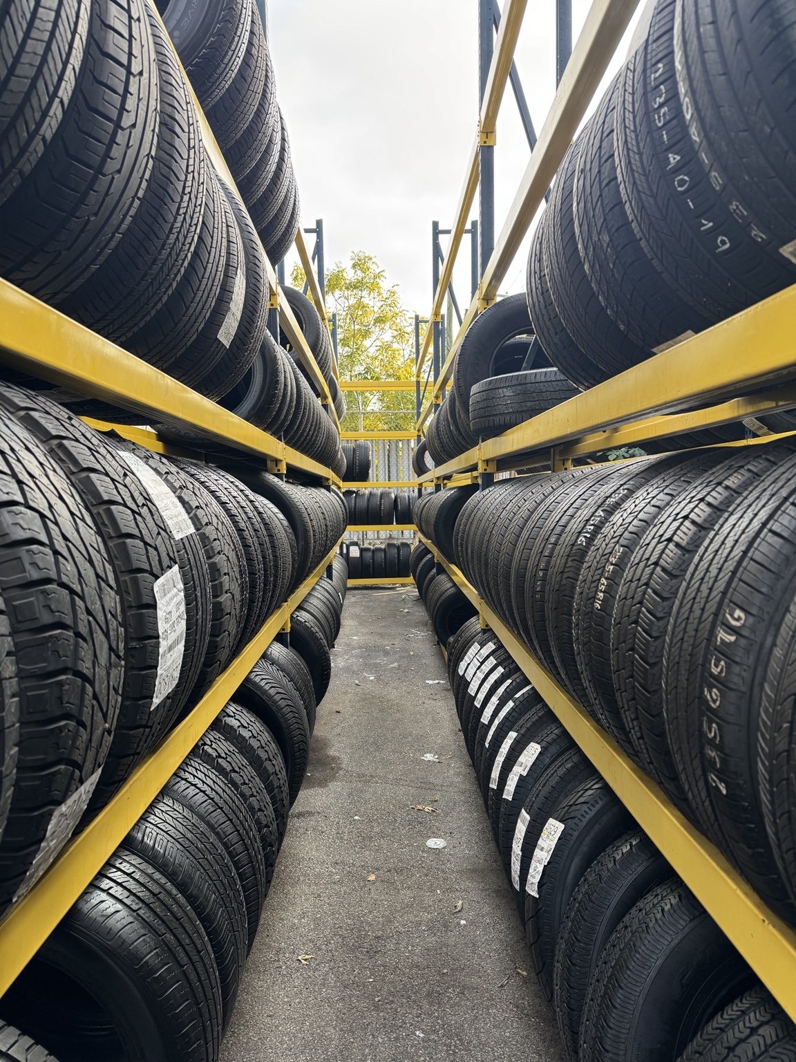Actual new and used tire inventory displayed on yellow racks at Marquez & Sons
